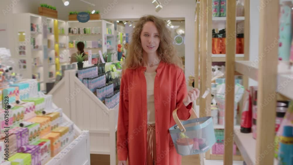 Portrait of young smiling customer holding shopping basket with cosmetic purchases, looking at camera Portrait of young smiling customer holding shopping basket with cosmetic purchases, looking at camera