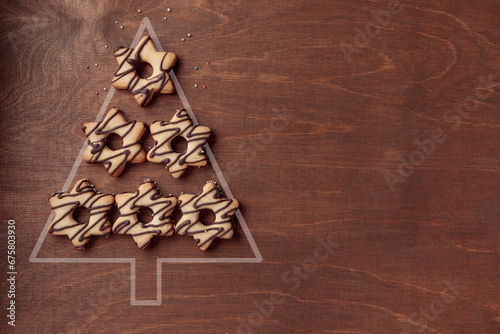 Christmas tree form made from star-shaped gingerbread cookies with chocolate on brown background