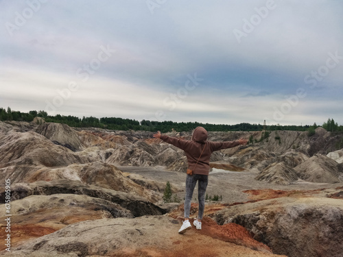 A girl on the background of the Ural Mars. An extraordinarily beautiful summer landscape with red lakes, colorful slopes and forest. Natural landscape, impressive sky. © Виктория Балобанова