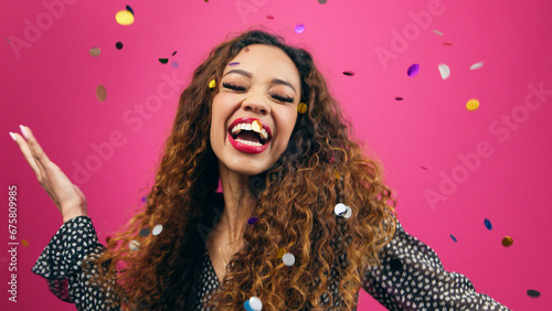 Beautiful young woman dances while multi-coloured confetti rains down