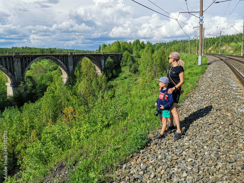 Railway bridge across the river in the south of the Kama region. A girl with a child on the background of the old viaduct of the Big Sars. The abandoned Oktyabrsky viaduct in the Perm Region. Russia. photo