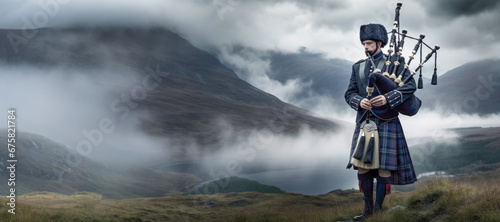 A man in traditional Scottish attire, including a kilt, plays the bagpipes by the misty lakeside in summer. photo