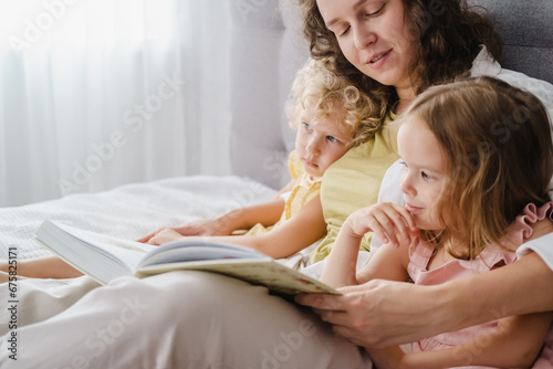 Mother reading a book her daughters at home