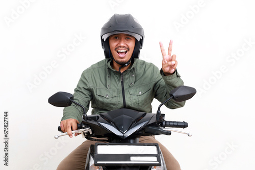 Happy asian man showing two fingers while driving motorcycle. Isolated on white background photo