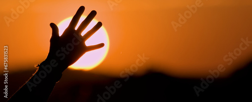 Silueta de mano abierta a contraluz con el sol de fondo al amanecer. Vida saludable, naturaleza y libertad