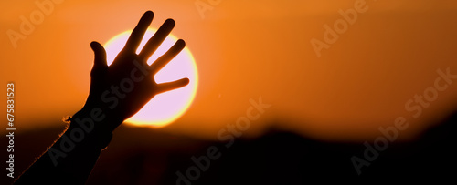 Silueta de mano abierta a contraluz con el sol de fondo al amanecer. Vida saludable, naturaleza y libertad photo