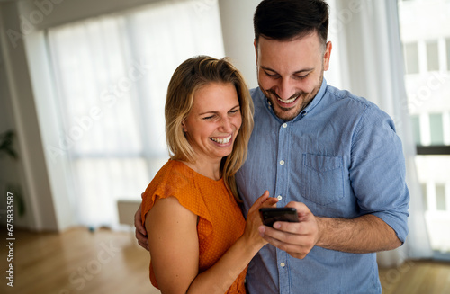 Portrait of happy couple having fun, using smartphone together. People technology concept