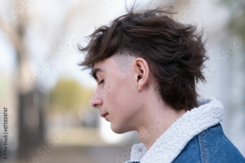 Young male with a trendy haircut standing in a city street in a denim jacket © Wirestock