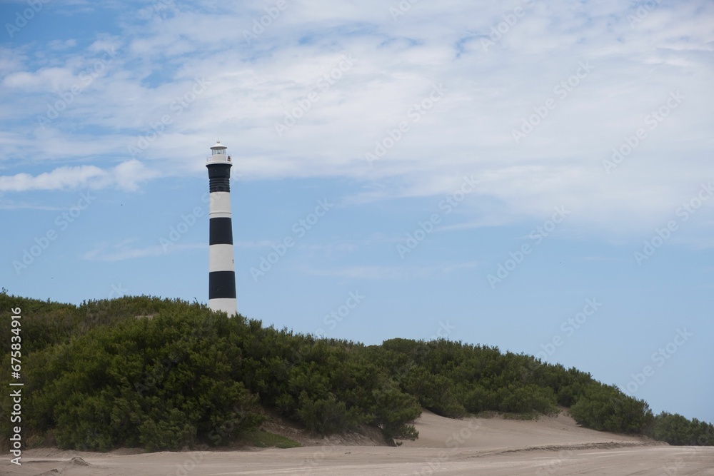 a beach with sand and a lighthouse tower on top of the hill a beach with sand and a lighthouse tower on top of the hill