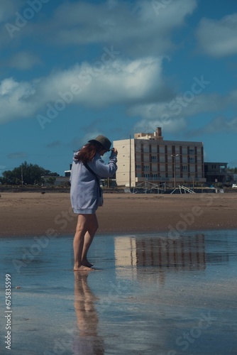 Barefoot woman walking along the sandy beach. © Wirestock