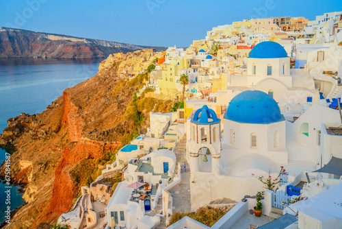 traditional greek village Oia of Santorini, with blue domes of churches and village roofs in soft morning light, Greece