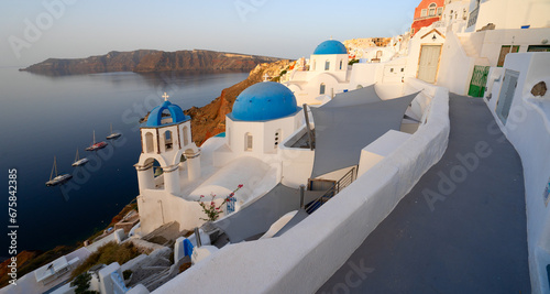 street of traditional greek village Oia of Santorini, with blue domes against Aegan sea and caldera, Greece, web banner format