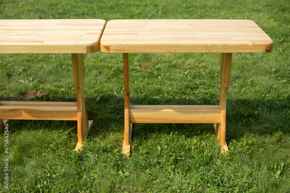 Wooden table on a green lawn. Wooden furniture in the park. Empty tables. Wooden table on a green lawn. Wooden furniture in the park. Empty tables.