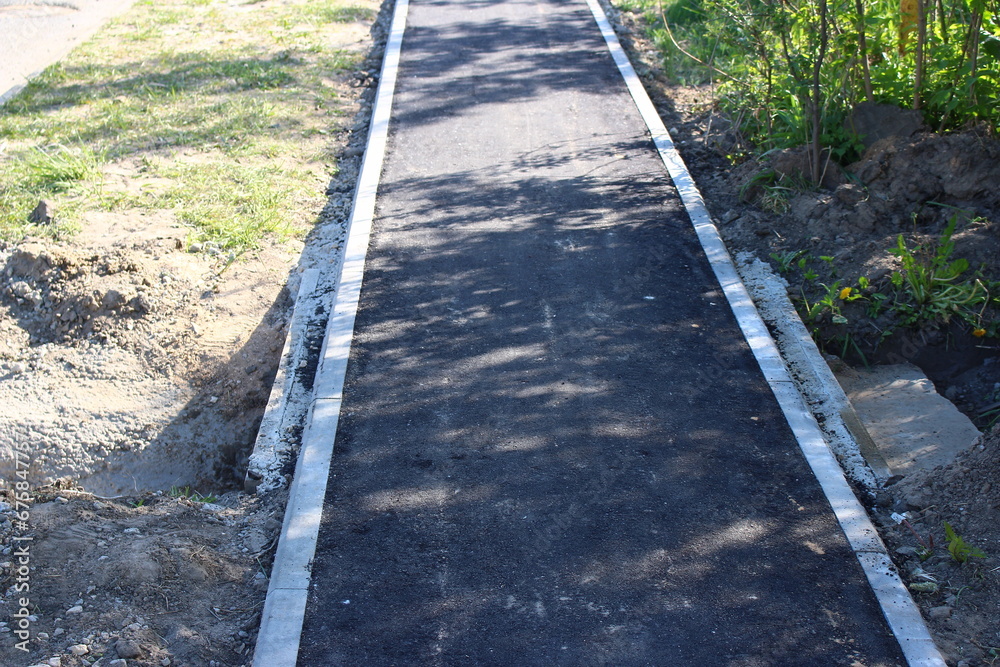 Paved asphalt pedestrian path, narrow sidewalk on the street Paved asphalt pedestrian path, narrow sidewalk on the street