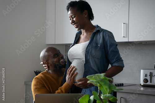 Valokuva Smiling man touching pregnant woman's belly in kitchen