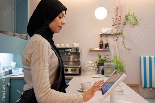 Young woman in hijab working in cafe