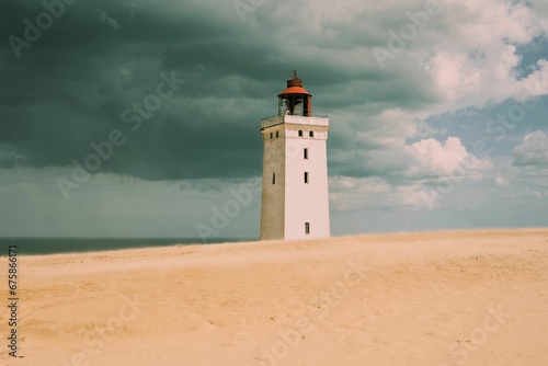 there is a small lighthouse on the beach under a stormy sky