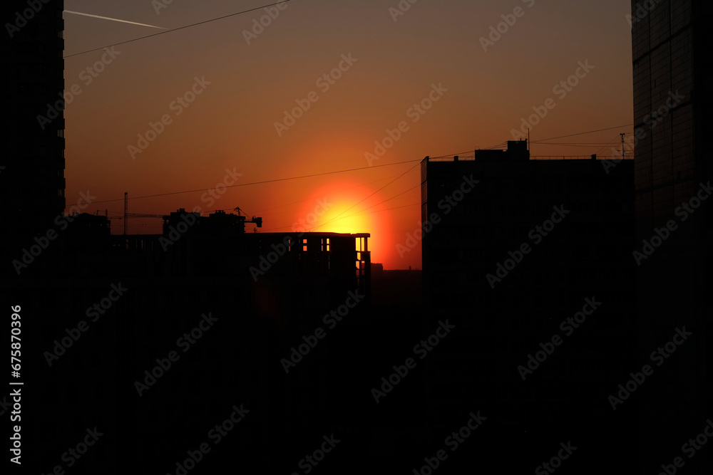 Halo effect in the evening sky, red sun on sunset in being constructed buildings silhouettes