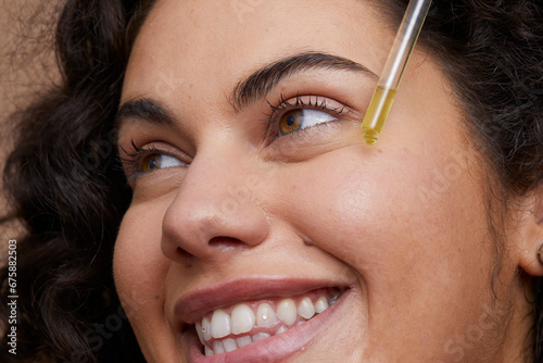 Close-up of young woman applying face serum photo