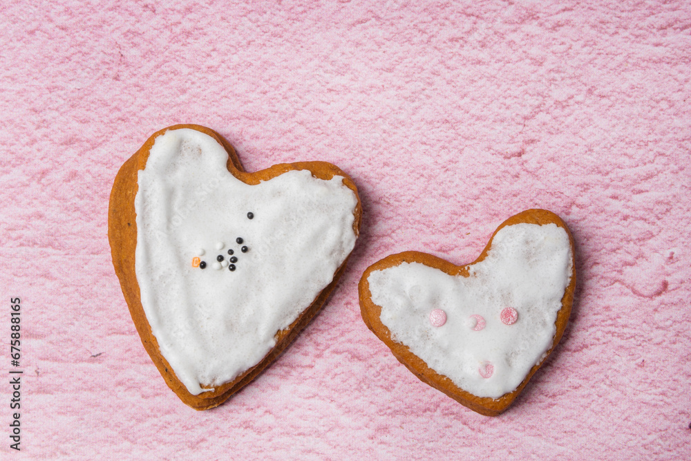 Obraz premium Two gingerbread cookies with white icing are on a pink background