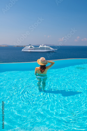 Tourist enjoying at the infinity pool with cruise view, Mykonos, Greece