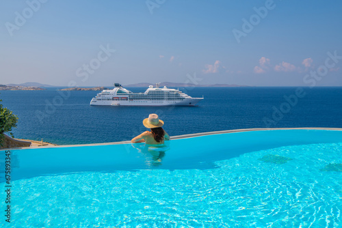 Tourist enjoying at the infinity pool with cruise view, Mykonos, Greece photo