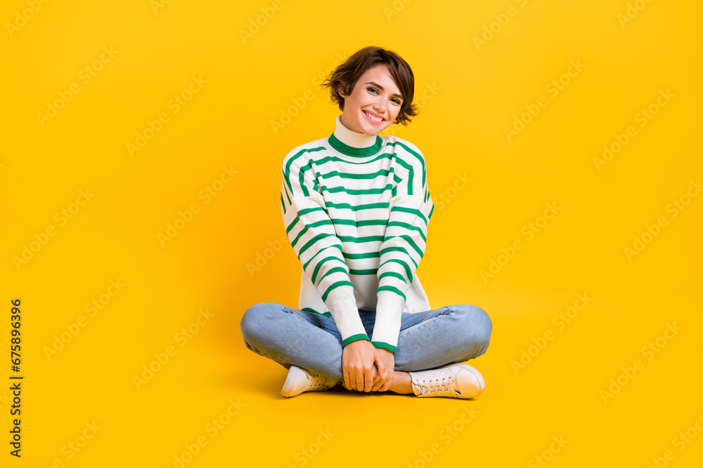 Full length body photo of young charming girlfriend sitting crossed legs comfortable floor relax isolated on yellow color background Full length body photo of young charming girlfriend sitting crossed legs comfortable floor relax isolated on yellow color background