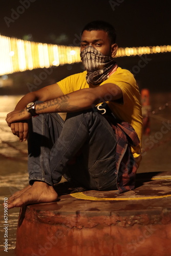 Indian man sitting on tha branch near river 