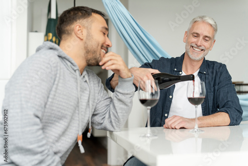 Male couple pouring red wine at home