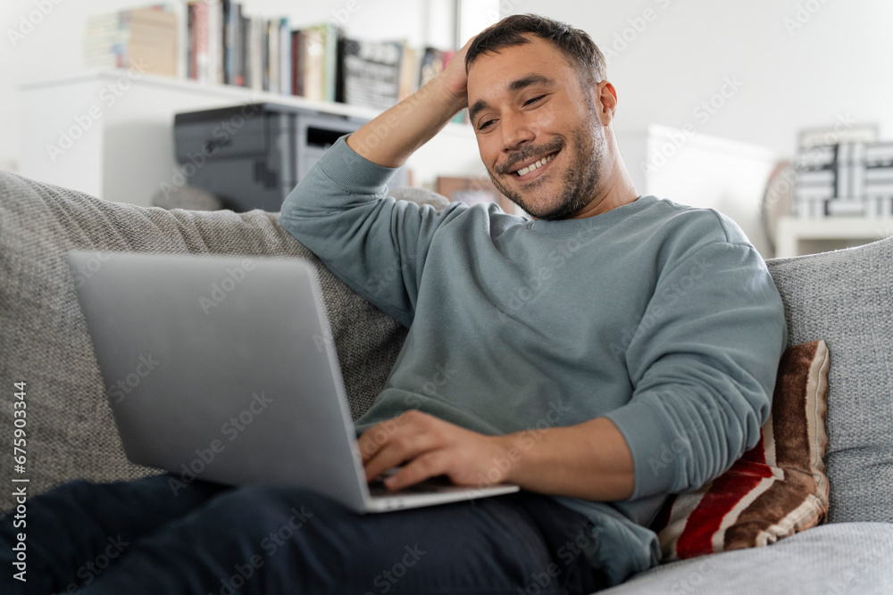 Smiling mature man working on laptop on sofa Smiling mature man working on laptop on sofa