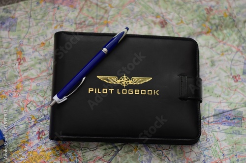 Top view of a pilot's logbook with a pen on the map on the table
