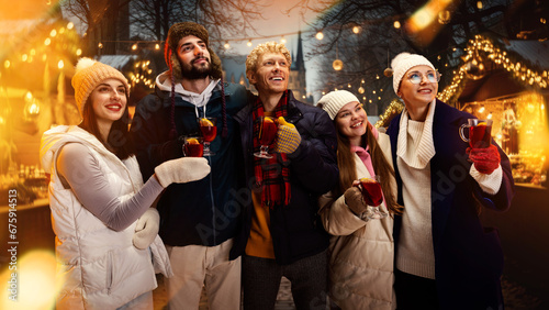 Group portrait of happy cheerful people, friends with cup of hot warming mulled-wine and enjoying moment before New Year Day.