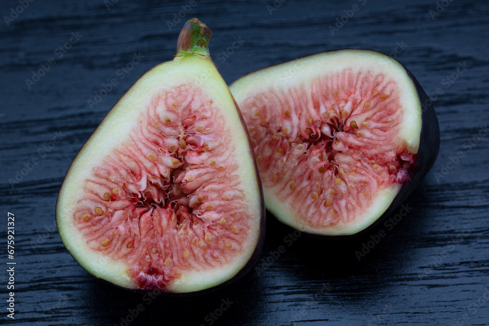 Fig halves in macro on black wood background of food still life Fig halves in macro on black wood background of food still life