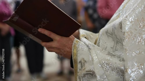 An Orthodox priest stands in a church and reads the Bible. The priest preaches.