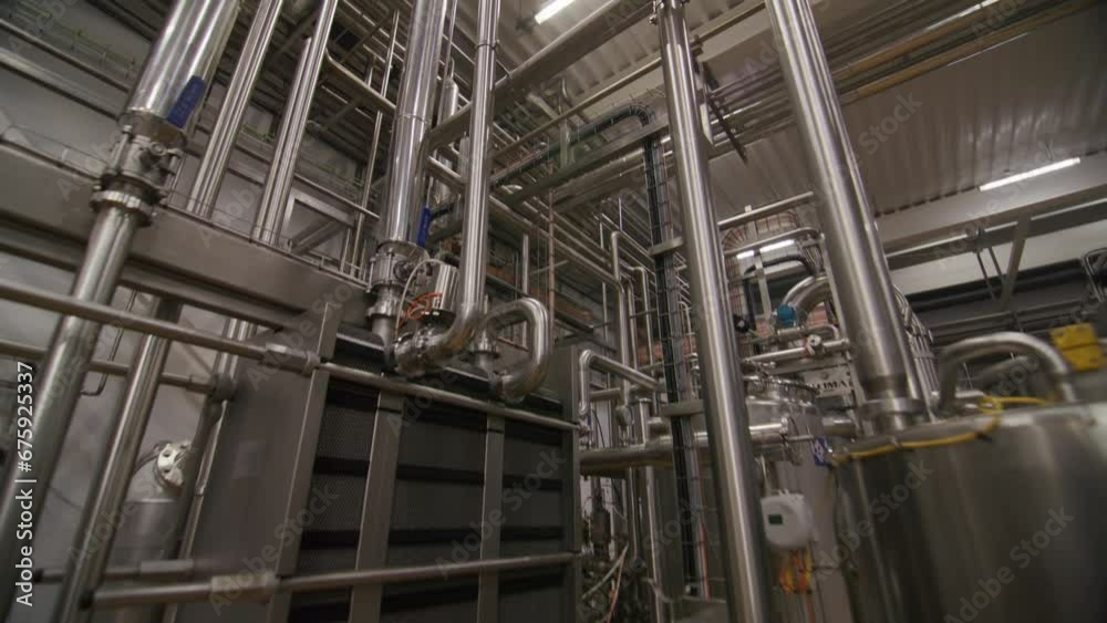 Pipeline system over tank and pump in chemical plant workshop. Equipment used to produce biochemical fertilizers at modern factory Pipeline system over tank and pump in chemical plant workshop. Equipment used to produce biochemical fertilizers at modern factory