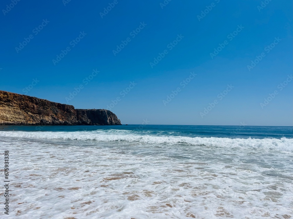 Ocean coastline, rocky coast, sandy beach, foam at the ocean shore