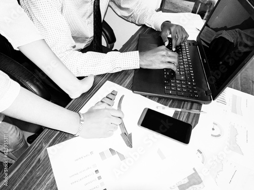 Two young adult man woman indian working together on desk with graphs in the office. Aerial view