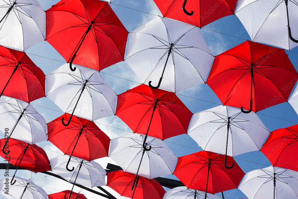 Poland National Independence Day background. Red and white Polish flag colors. Umbrellas hanging over head against blue sky. 11 November in Poland. Celebrating a holiday. Symbolic background.