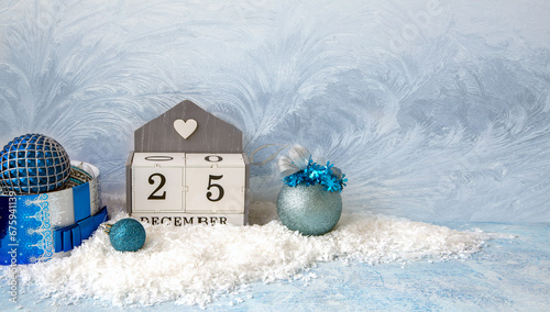 Christmas mood, New Year background. Sparkling Christmas balls on the snow and a calendar with the date December 25 with copy space. The atmosphere of the holiday.