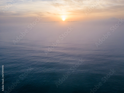 Aerial view of a sunrise sea with a blanket of morning fog and morning sunbeams shining through