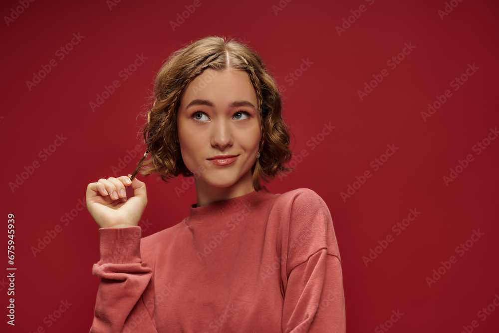 portrait of young pensive woman with short wavy hair and braids looking away on red background portrait of young pensive woman with short wavy hair and braids looking away on red background