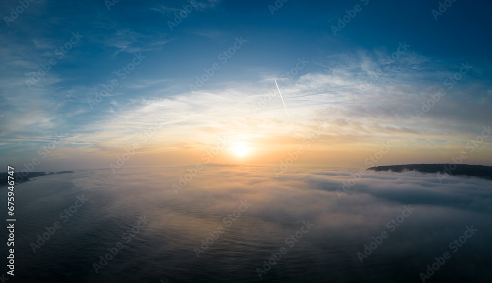 Aerial view of a sunrise sea with a blanket of morning fog and morning sunbeams shining through Aerial view of a sunrise sea with a blanket of morning fog and morning sunbeams shining through