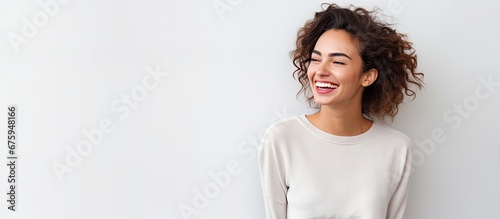 A woman with braces stands against a white wall smiling happily as people in the background admire her fashion sense and appreciate her beauty in a space isolated for medical health photo