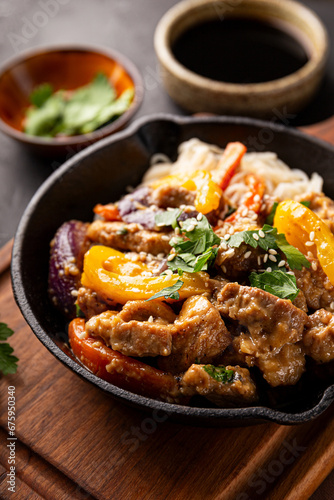 Asian pork with vegetables and glass noodles in a pan on the black background vertical photo