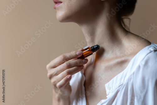 Woman applying natural rollerball aroma oil on her neck  close up	