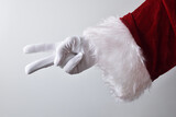 Santa Claus hand showing two fingers wearing gloves dressed traditionally