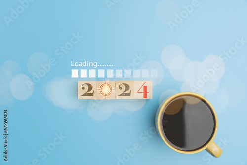 2024 on wooden cube blocks with coffee of cup, and virtual screen loading on blue background, New Year countdown, beginning new year, planning of strategy marketing set target challenge for business.