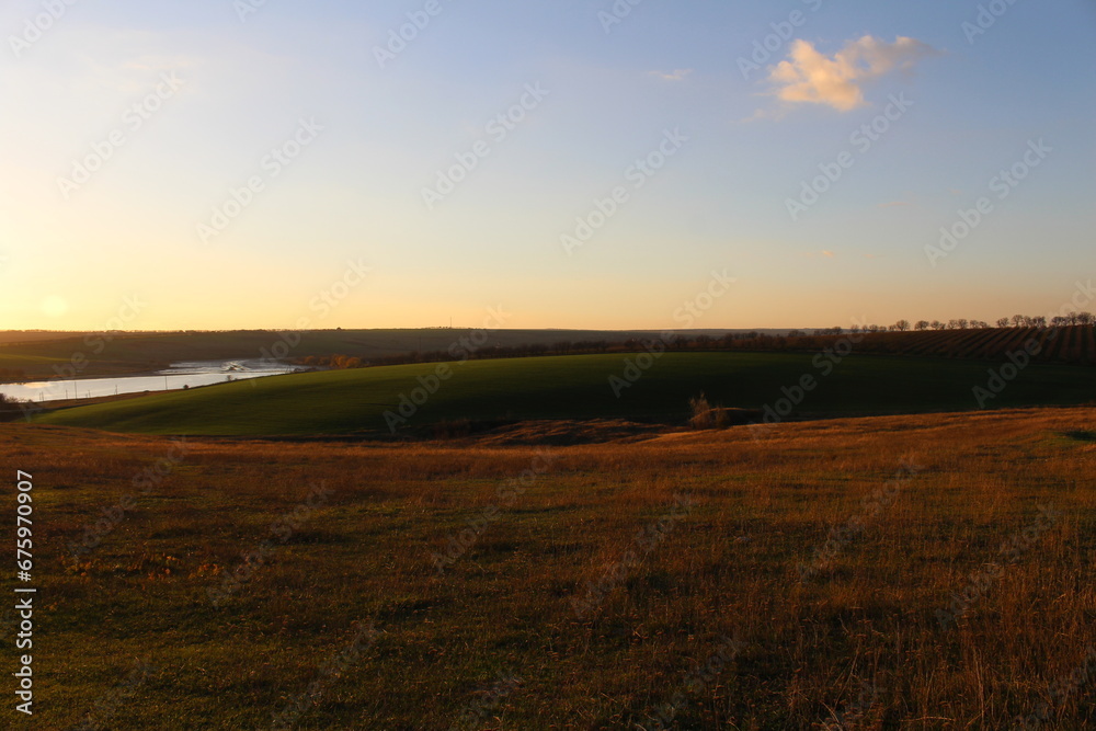 A grassy field with a body of water in the distance