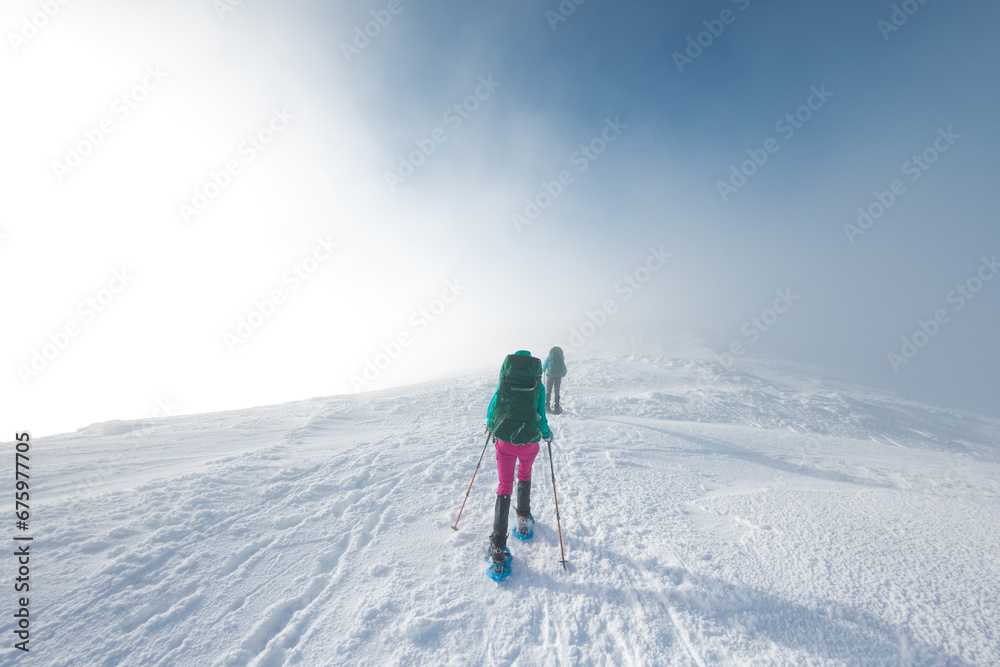 two tourists in winter mountains on snowshoes