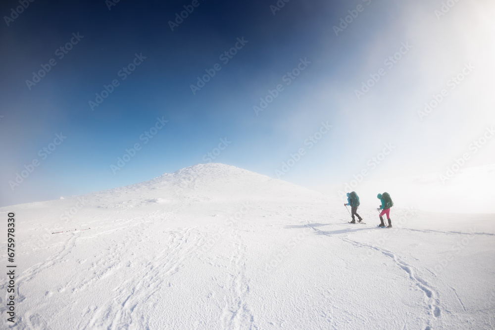 climbers climb the mountain in the snow. Winter mountaineering. two girls in snowshoes walk through the snow. mountaineering equipment. hiking in the mountains in winter.